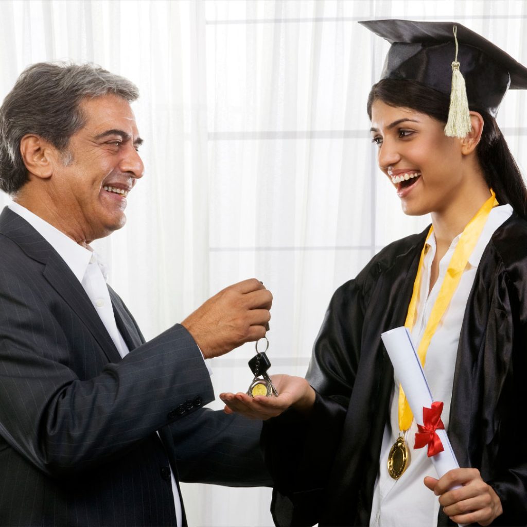 A female graduate receives car keys from her father.