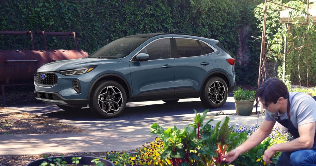 A blue 2026 Ford Escape sits parked in a driveway of a family home.